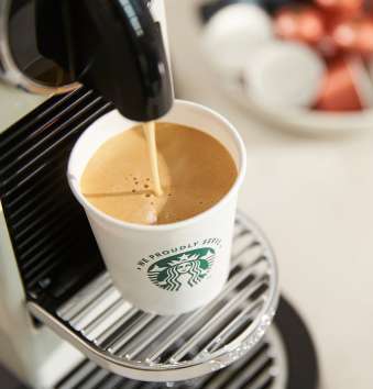 一個印有 We Proudly Serve Starbucks 星巴克咖啡服務字樣的杯子裝滿由單杯濃縮咖啡機新鮮沖泡的咖啡