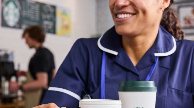 一群醫護人員坐在醫院咖啡廳裡，手裡拿著印有 We Proudly Serve Starbucks 星巴克咖啡服務字樣的飲品